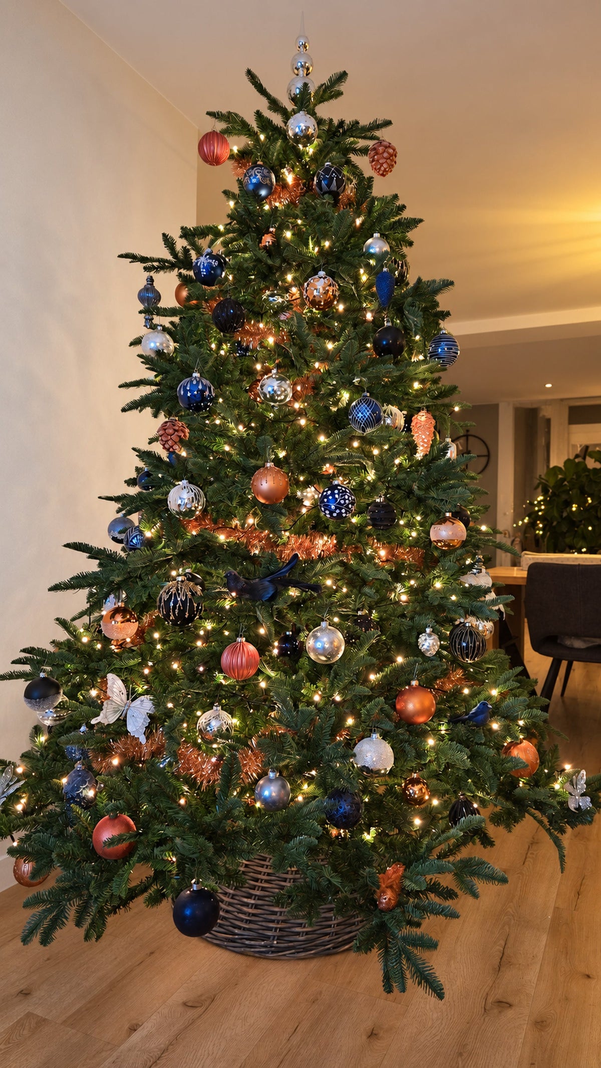 Volle kerstboom van 230 centimeter met zo'n 250 kerstballen en ornamenten in koper en blauw